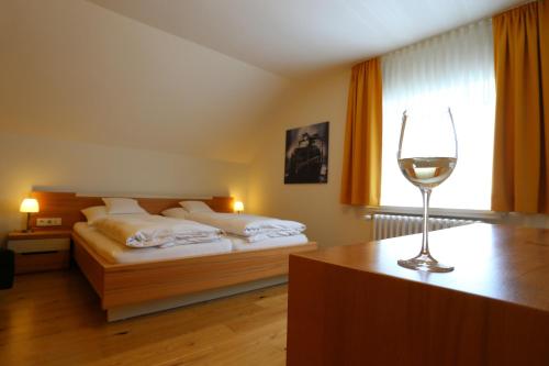 a bedroom with a bed and a glass of wine at Ernst Clüsserath Weingut & Weinhotelchen in Trittenheim