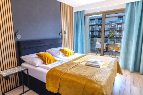 ein Schlafzimmer mit einem Bett mit gelber Bettwäsche und einem Fenster in der Unterkunft Apartament Opal - Family & SPA in Dziwnów
