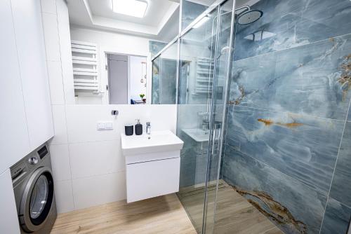 a bathroom with a shower and a sink and a washing machine at Apartament Opal 34 Family & SPA in Dziwnów