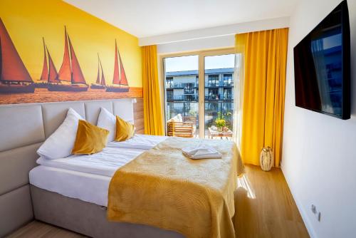 1 dormitorio con 1 cama con paredes amarillas y TV en Apartament Opal 34 Family & SPA, en Dziwnów