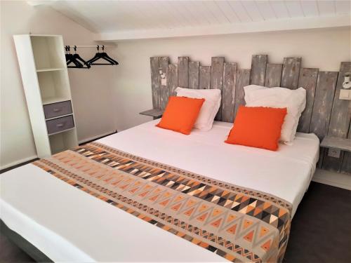Duas camas com almofadas laranja num quarto em Gîte Cannelle em Saint-François