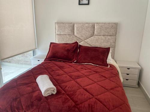 uma cama vermelha com almofadas vermelhas e um cobertor vermelho em Centro Internacional - La Quinta em Bogotá