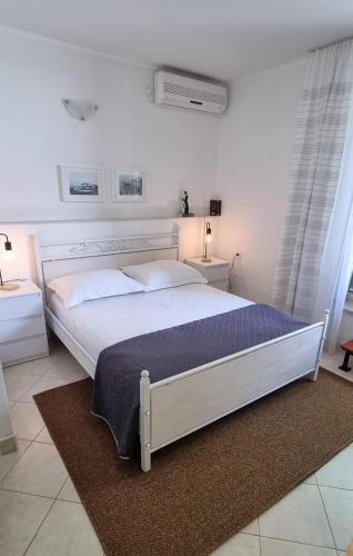 a white bed in a white bedroom with two tables at Apartments by the sea Postira, Brac - 706 in Postira