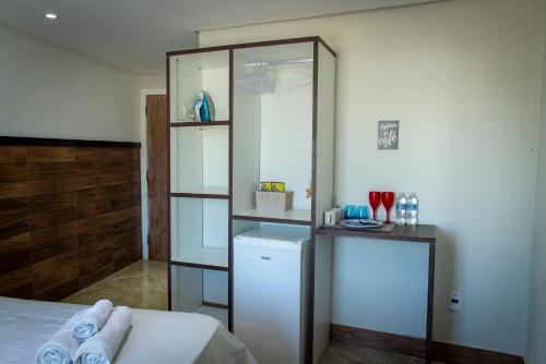 Schlafzimmer mit einem weißen Bett und einem Spiegel in der Unterkunft Suit's Bella Vista Arraial do Cabo in Arraial do Cabo