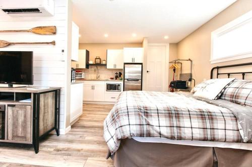 a bedroom with a bed and a kitchen at RainCoast Retreat at Shawnigan Lake! in Shawnigan Lake