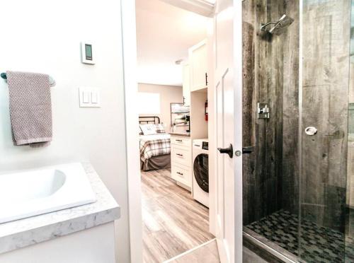uma casa de banho com um lavatório e um chuveiro com uma porta de vidro em RainCoast Retreat at Shawnigan Lake! em Shawnigan Lake