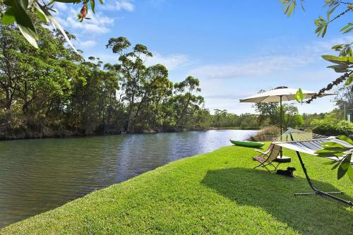 a table and an umbrella next to a river at Lake Frontage in Lake Tabourie