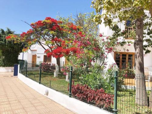 a fence in front of a house with red flowers at Apartamento Lucía Garden City con piscina climatizada in Playa Fañabe