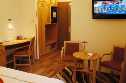 a living room with a table and a television on the wall at Hotel Manzard Panzio in Budapest