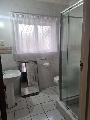 a bathroom with a shower and a sink and a toilet at Home Feeling Guesthouse in Port Shepstone