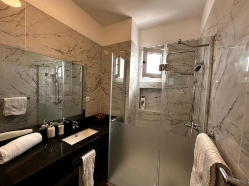 a bathroom with a sink and a shower with a glass door at Casa de Ferias dos Marmeleiros in Funchal