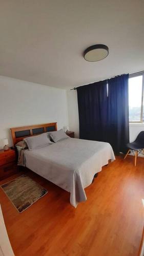 a bedroom with a large bed with a blue curtain at Departamento en Parque O'higgins in Santiago
