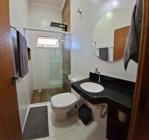 a bathroom with a toilet and a sink and a mirror at Solarium Flats Itagua - Ubatuba SP in Ubatuba