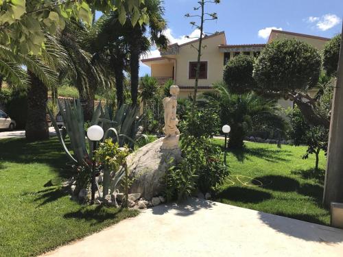 a statue sitting on top of a rock in a yard at Villa Marina B&B in Cleto
