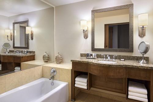 a bathroom with two sinks and a tub and a mirror at JW Marriott Tucson Starr Pass Resort in Tucson