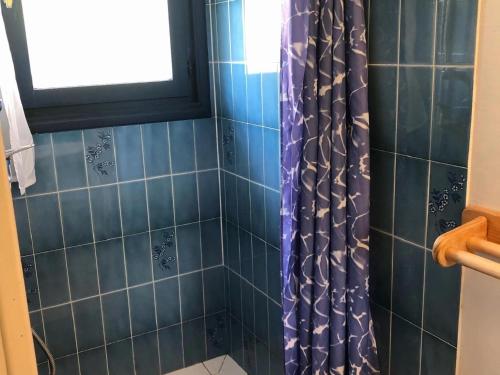 a bathroom with a shower with blue tiles and a window at Gîte de la Marandine in Métabief with garden in Métabief