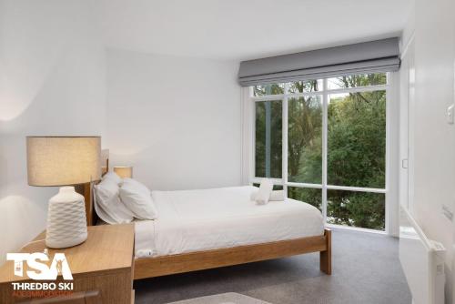 a bedroom with a bed and a large window at Chalet 26 in Thredbo