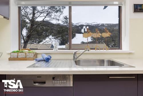 eine Küchentheke mit einem Waschbecken und einem Fenster in der Unterkunft Mowamba B2 in Thredbo