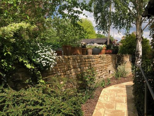 a brick retaining wall with potted plants on it at 1A Erneston Crescent in Corsham