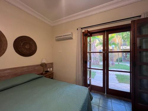 um quarto com uma cama e uma porta de vidro deslizante em Suite 1110 IlhaFlat em Ilhabela