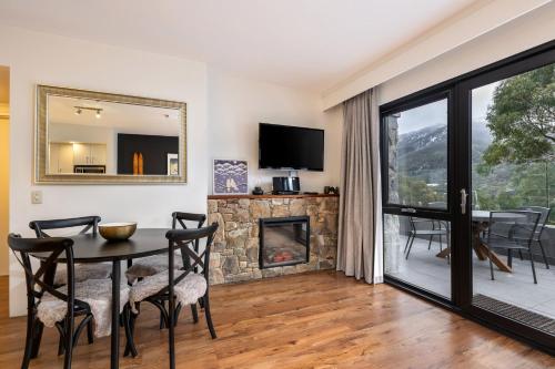a dining room with a table and a fireplace at Lantern 10 Deluxe - Parking in Thredbo