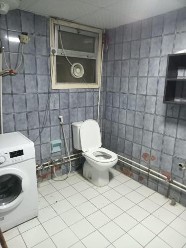 a bathroom with a toilet and a washing machine at Partition Al rigga in Dubai