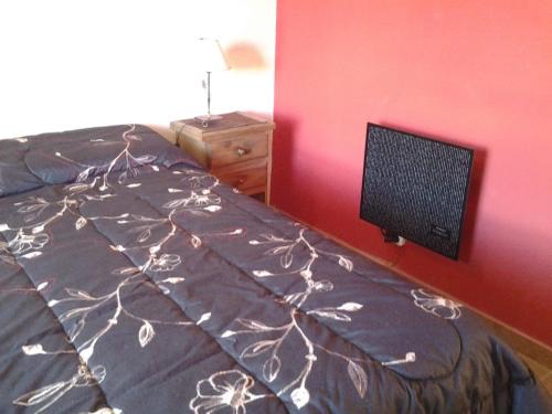 a bedroom with a bed and a tv on a wall at Cabañas Lunas y Soles in Potrero de los Funes