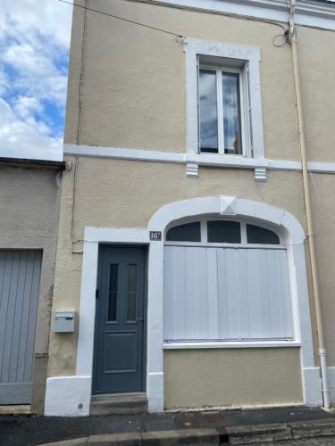 a house with a blue door and a white garage at La Petite Maison in Châteauroux
