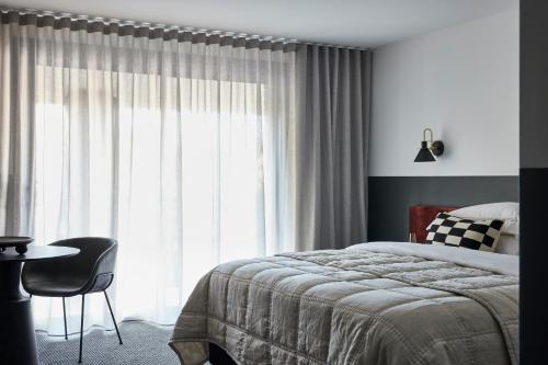 a bedroom with a bed and a table and a window at Central Caleula Motor Lodge in Orange