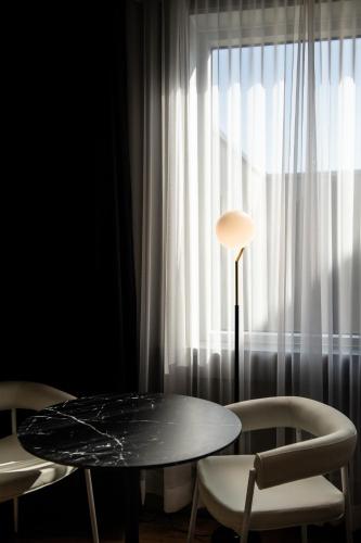 a table and two chairs in front of a window at Hotel Chicoutimi, affilié à Hyvi in Saguenay
