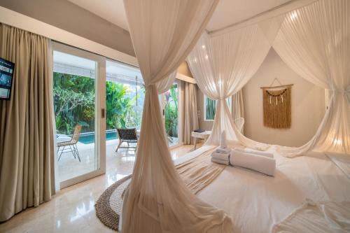 una camera da letto con un letto bianco e zanzariere di Villa Charles Ubud ad Ubud