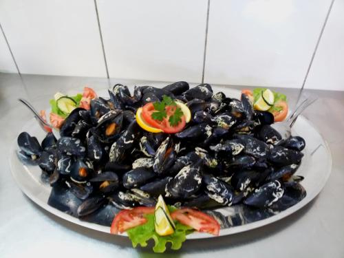 a plate of mussels with a tomato and salad at Rooms Ante in Tribanj-Krušćica