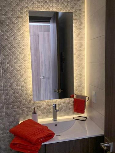 a bathroom with a sink with a mirror and red towels at Confort suite La Carolina in Quito