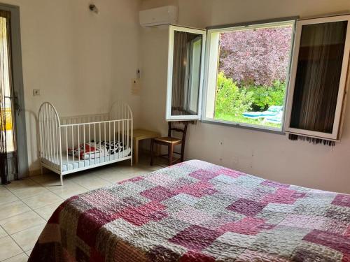 ein Schlafzimmer mit einem Bett, einem Fenster und einem Kinderbett in der Unterkunft Le Romulus in Roumoules