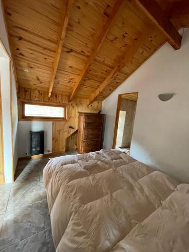 um quarto com uma cama e um tecto de madeira em La Casa de Belen em San Martín de los Andes