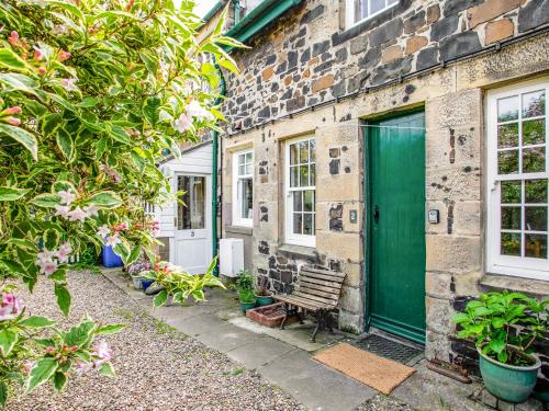 a green door on a brick building with a bench at Elliot Cottage in Bamburgh