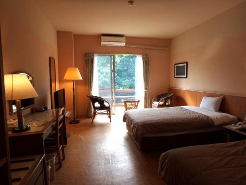西表島にある西表島ジャングルホテル パイヌマヤのベッド2台と窓が備わるホテルルームです。