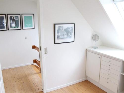 um quarto com paredes brancas e uma escada com quadros na parede em Holiday home Svaneke II em Svaneke