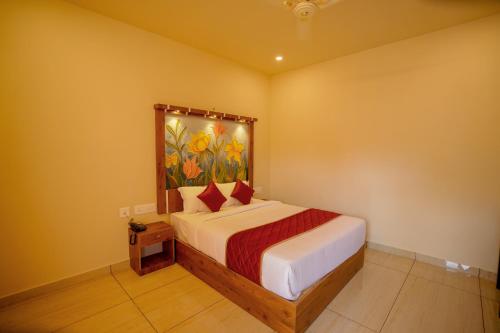 a bedroom with a bed with a painting on the wall at KOTTACKAL NATURE INN in Angamaly