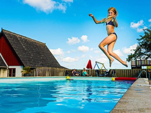 a young woman jumping into a swimming pool at 6 person holiday home in Allinge in Allinge
