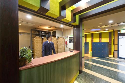 a man standing at a counter in a lobby at International Hotel Kabukicho in Tokyo