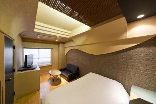 a hotel room with a bed and a tv and a chair at International Hotel Kabukicho in Tokyo