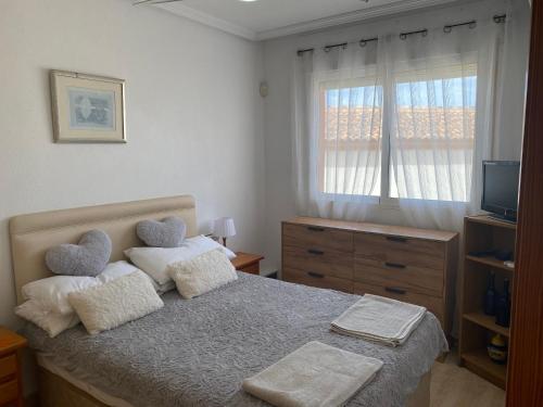 a bedroom with a bed with two pillows and a window at Luxurious 2 bedroom apartment near Cabo Roig strip in Playas de Orihuela