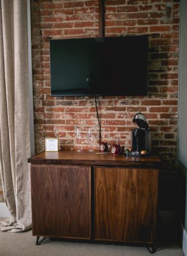 a wooden cabinet with a television on a brick wall at Historic Jacksonville Inn in Jacksonville