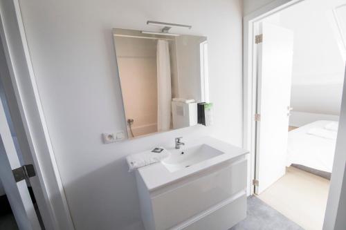 a white bathroom with a sink and a mirror at Smart Appart - Clmenceau in Brussels
