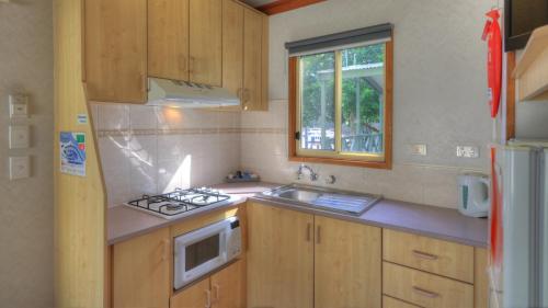 a small kitchen with a stove and a sink at Moama Riverside Holiday Park in Moama