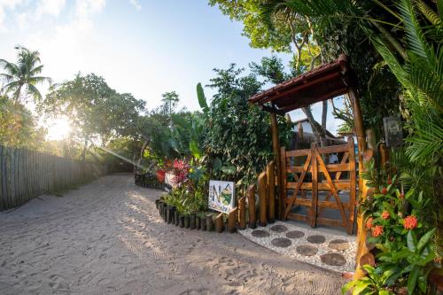 ogród z bramą i kwiatami na plaży w obiekcie Pousada NÔ Caraíva w mieście Caraíva