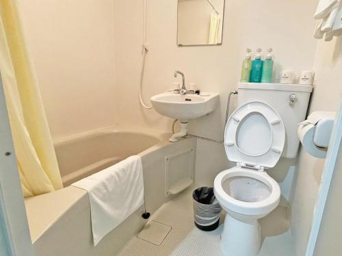 a white bathroom with a toilet and a sink at Victoria Hotel in Naha