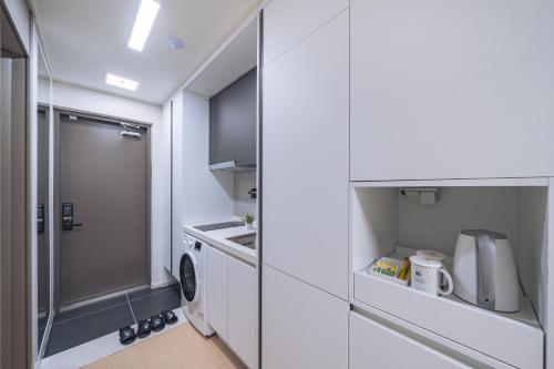 チュンチョンにあるChuncheon Bella Residenceの白い小さなキッチン(洗濯機、乾燥機付)