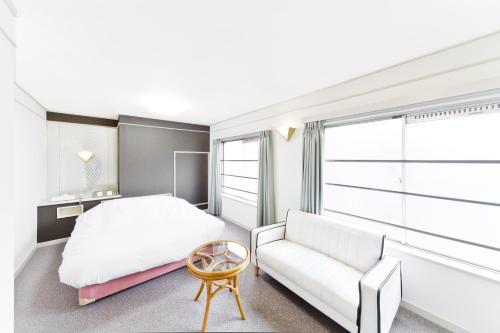 ein Schlafzimmer mit einem weißen Bett und einem Sofa in der Unterkunft Shinjuku East Hotel in Tokio